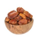 dried dates in a wooden bowl isolated on white background
